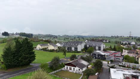 traffic on road in small swiss town during grey sky with snow on roofs
