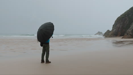 person with umbrella on a vast, overcast beach