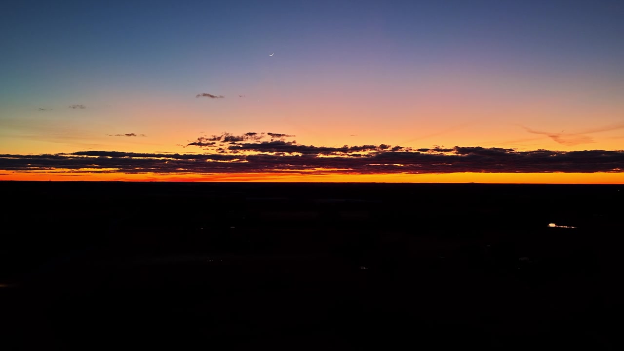 Beautiful and colorful sunset with the crescent moon rising over the horizon