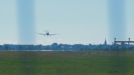 pequeño avión de entrenamiento blanco con motores de hélice aterrizando en el aeropuerto en un día soleado de verano, plano medio desde la distancia