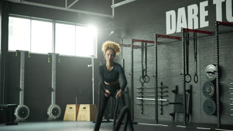 woman exercising with battle ropes in a gym