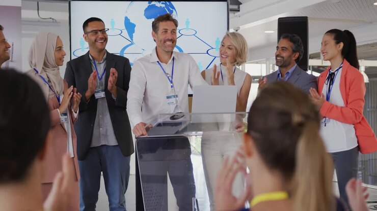 Male speaker and applauding audience and colleagues at a business conference
