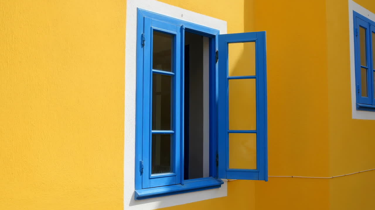 Blue Window with Open Shutters on a Bright Yellow Wall