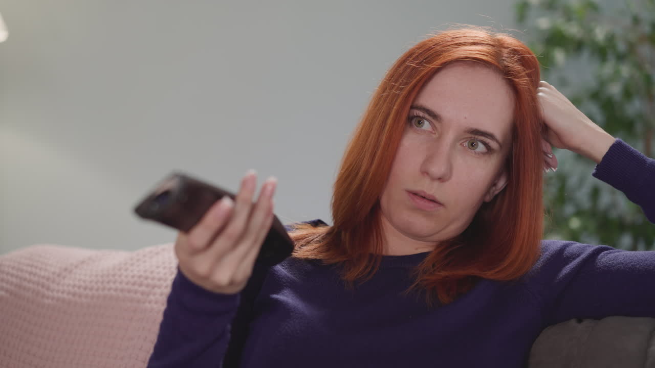 mujer angustiada trata de encontrar un programa de televisión para ver en casa