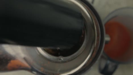 a lady putting a carrot into blending machine to get carrot juice from it