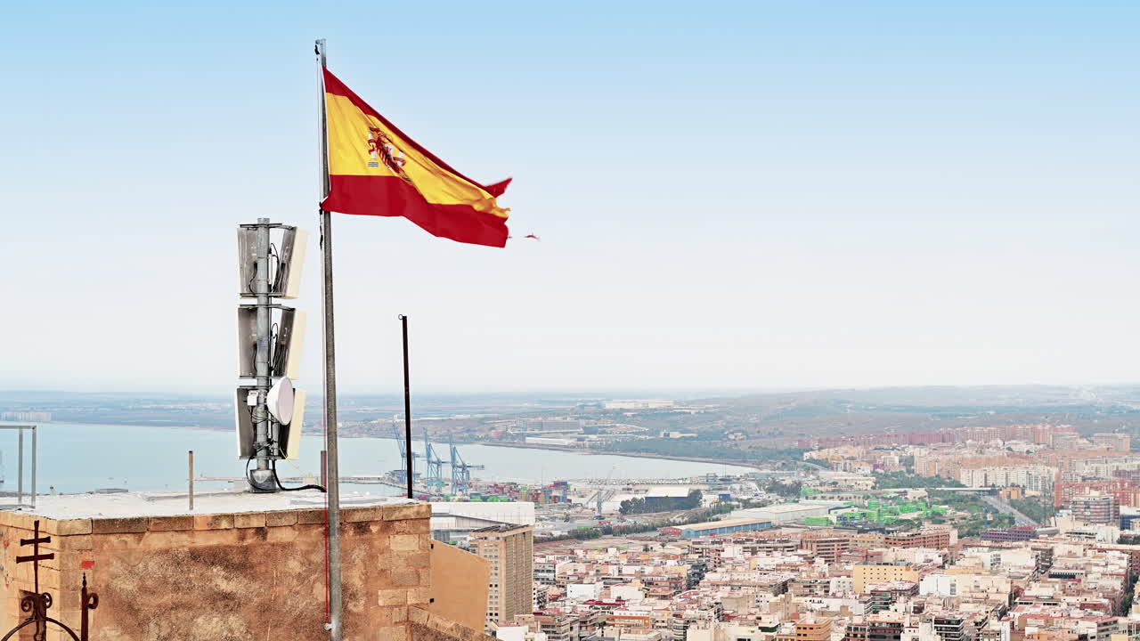Spanish flag waving on top of the town Alicante in Spain