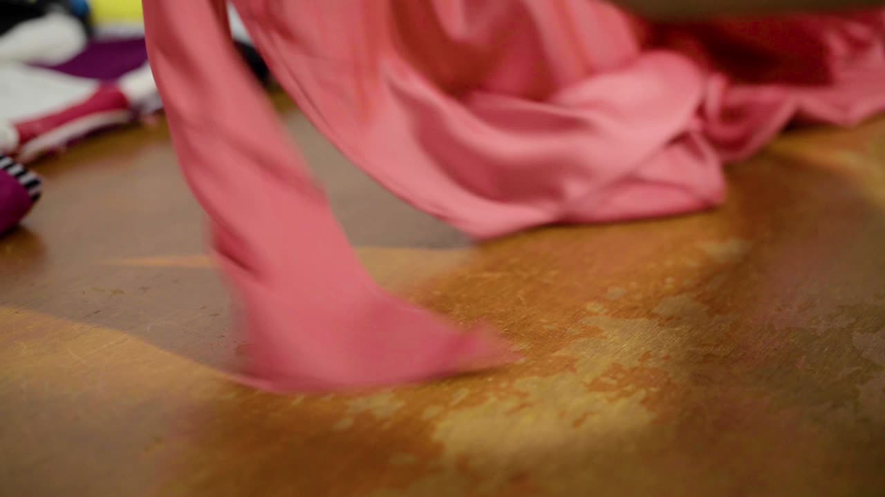 costurera latina cortando un vestido para ajustes usando tijeras en el taller sobre una mesa de madera