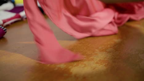 latin seamstress cutting a dress for adjustments using scissors at workshop on a wooden table