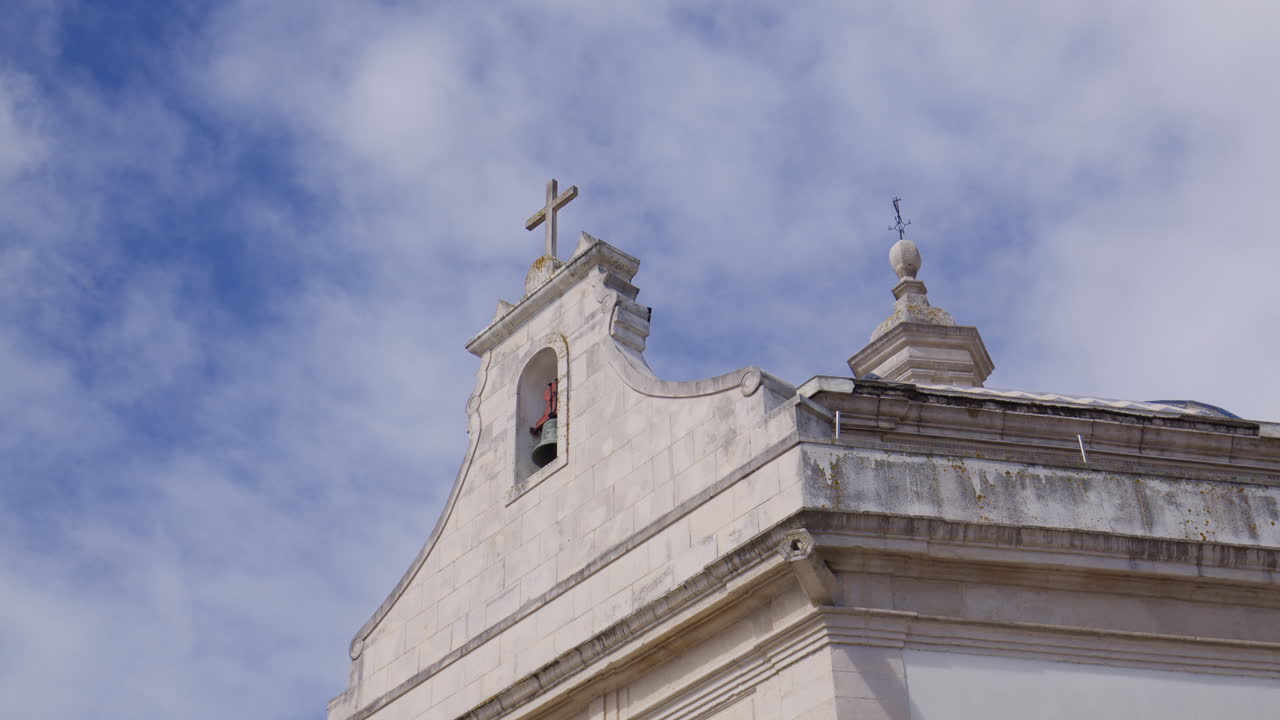 Chapel of Saint Goncalinho In Aveiro, Portugal - Stone Church Facade With Bell Tower And Cross Against Cloudy Blue Sky. low angle shot