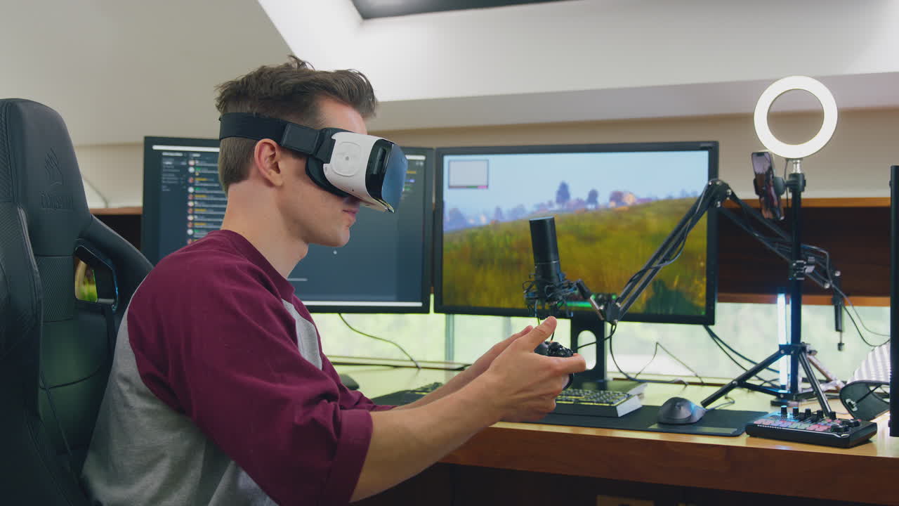 Man Wearing VR Or AR Headset Gaming At Home Sitting At Desk Live Streaming Shooting Game