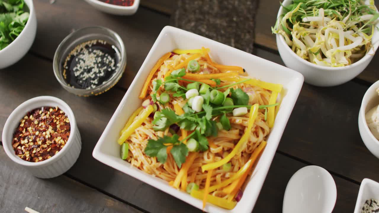 composición de cuencos con pad thai, verduras, salsas y especias sobre fondo de madera