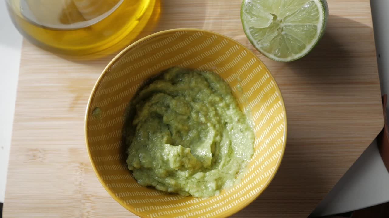Fresh guacamole being dipped with a tortilla chip, shot from above with a natural vibe