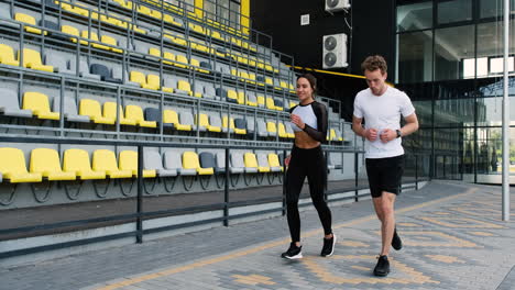 smiling sportive couple running together in the stadium