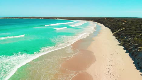 serene-coastal-bay-with-sparkling-blue-calm-and-clear-water-with-gentle-waves-lapping-against-the-shore-surrounded-by-lush-green-vegetation-and-rocky-cliffs