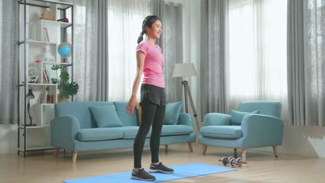 joven asiática deportiva haciendo ejercicio de agachamiento sola en la sala de estar, chica en forma seria con ropa deportiva agachada entrenando músculos ejercicios en casa para un cuerpo saludable concepto de estilo de vida