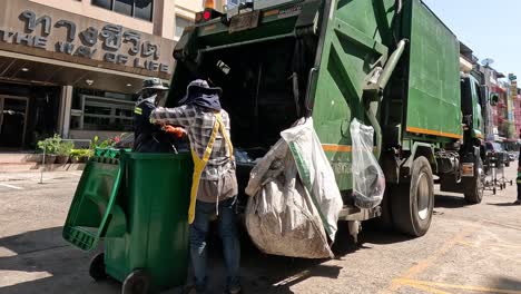 trabajador vacía contenedores en el camión de basura