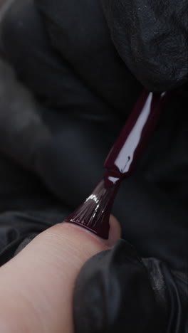 applying dark purple nail polish