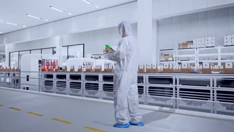 full body back view of asian male scientist use mock up green screen smartphone while standing with conveyor for packaging coffee beans in bags at coffee factory