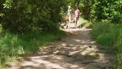 Happy-diverse-couple-hiking-with-backpacks-in-park,-slow-motion