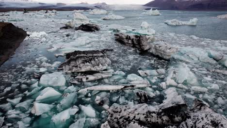 Grandes-Trozos-De-Hielo-En-El-Lago-Glacial-Jökulsárlón,-Islandia,-Descenso-Aéreo-Inclinado-Hacia-Arriba