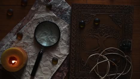 beautiful vintage background with ancient maps, a book, a candle some stones and a magnifying glass