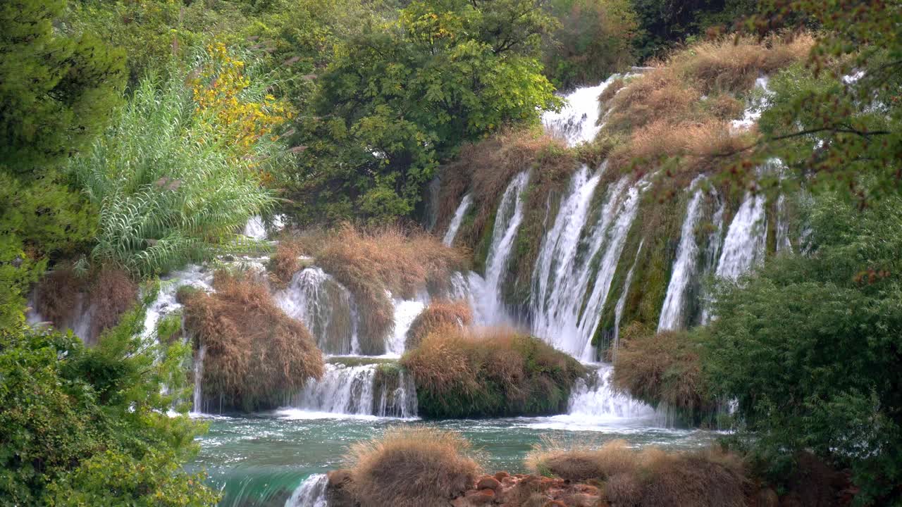 Una serie di cascate che scendono attraverso piante erbose brune in autunno nel Parco Nazionale di Krka in Croazia.