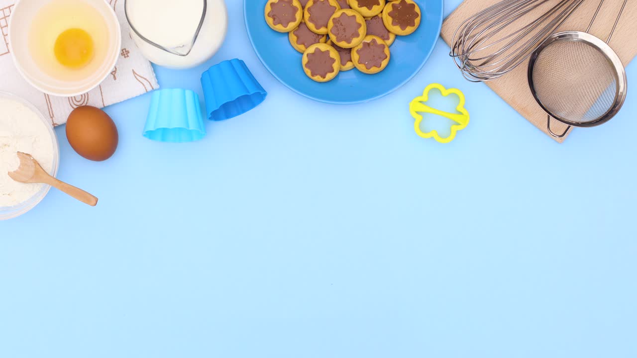las galletas en el plato azul y los ingredientes para hornear aparecen en la parte superior del tema azul. detenga el movimiento