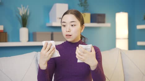 청년 아시아 여성은 청구서를 비교하는 동안 높은 가격의 청구서를 보고 우울해집니다.
