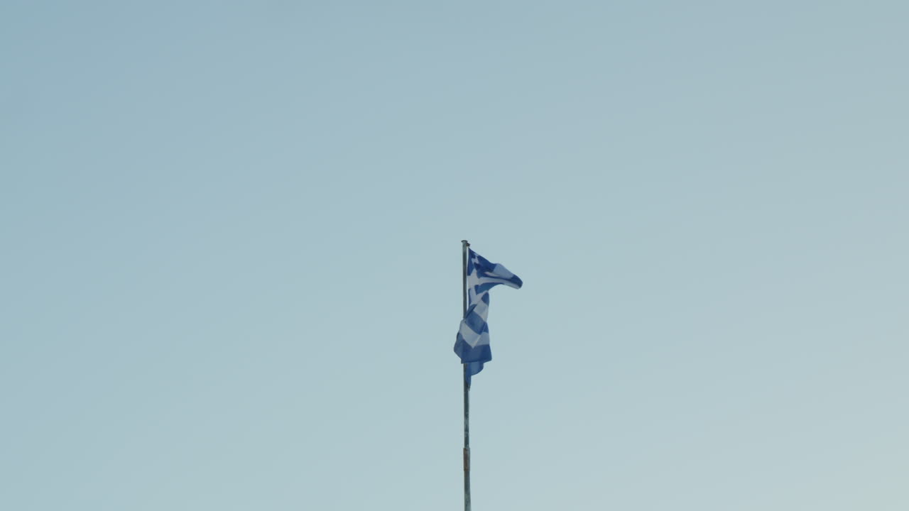 la bandera griega ondeando con orgullo contra un claro cielo azul
