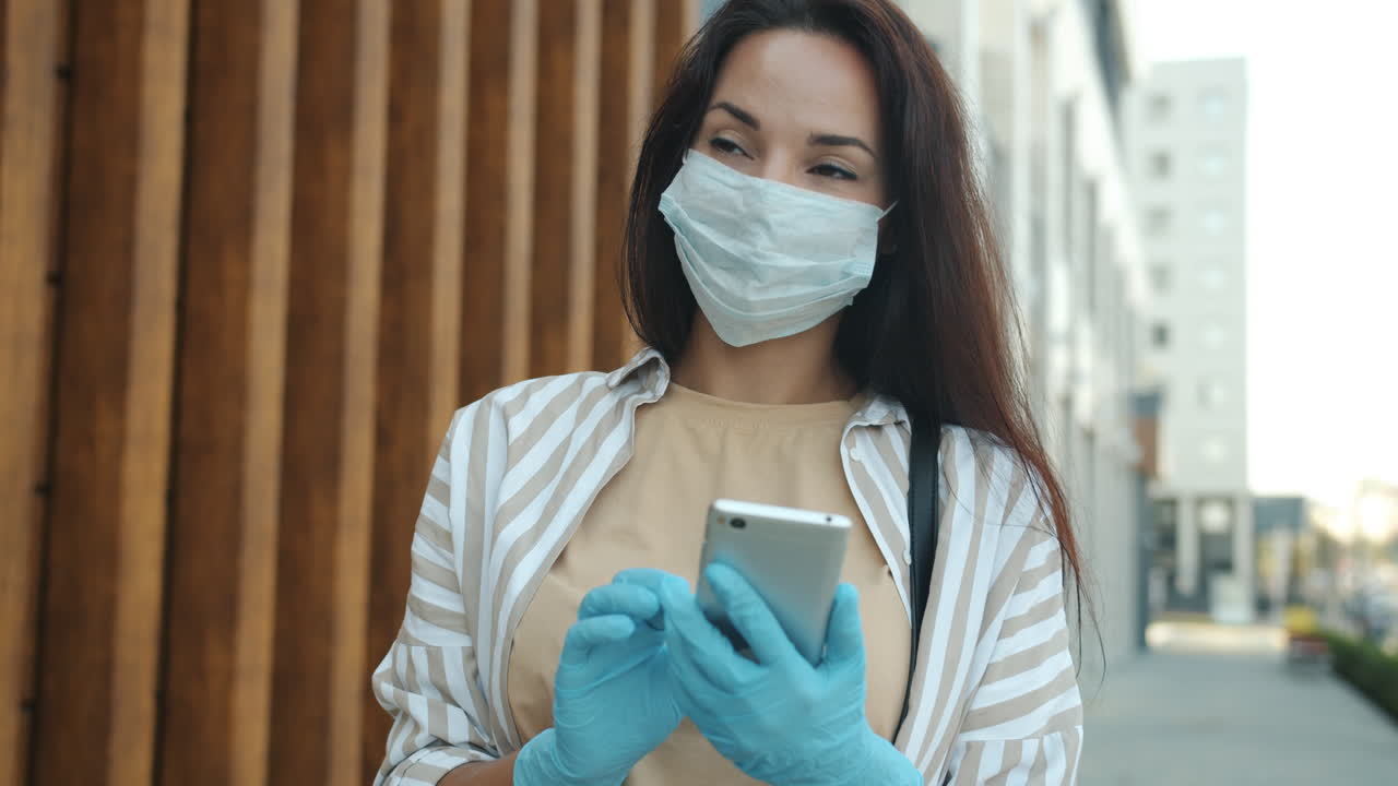 Woman using smartphone while wearing a mask and gloves