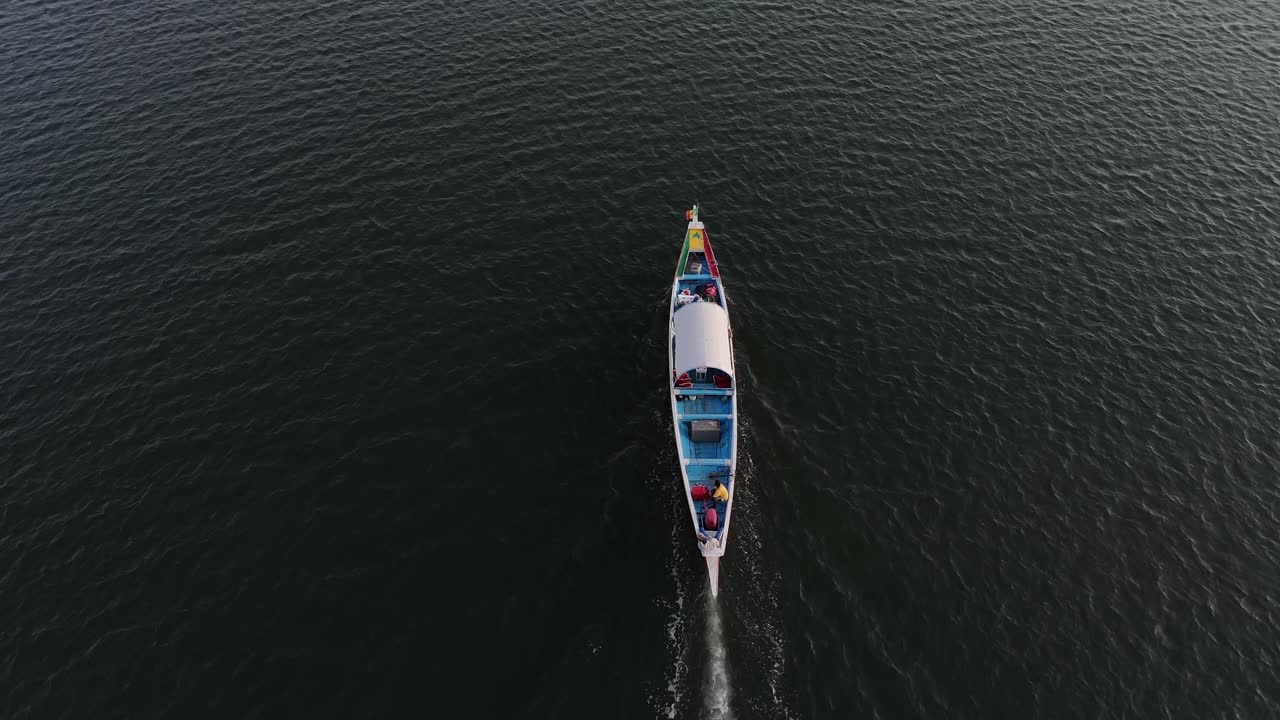 Vista aerea dall'alto di un drone che segue una tradizionale imbarcazione di legno che naviga attraverso i corsi d'acqua del delta del Sine Saloum in Senegal. Pittoresche mangrovie, zone umide e paesaggio naturale unico
