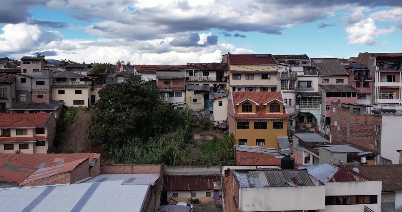 Metraje cinematográfico aéreo con dron capturando el centro histórico de Cuenca, Ecuador, y las famosas casas coloniales del Barranco con vistas al río Tomebamba en un hermoso día soleado y despejado en la ciudad.