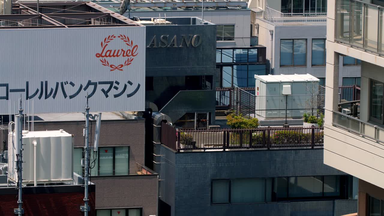 Building rooftops with commercial signs and gardens in the city downtown commercial area, Locked high view shot