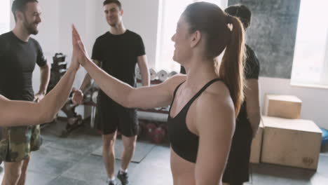 una joven fuerte ingresa al gimnasio y choca los cinco con sus compañeros