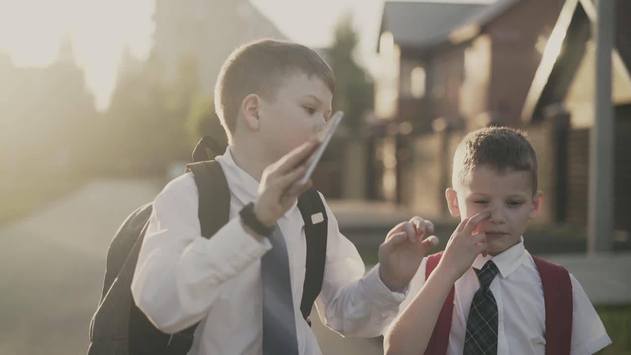 학교 졸업 후 집으로 돌아가는 두 명의 학생을 추적하고 그 중 한 명은 스마트폰을 들고 있습니다.