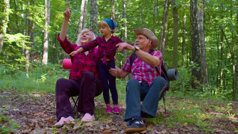 Active-senior-grandmother-grandfather-tourists-sitting,-hiking-with-granddaughter-in-summer-wood