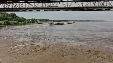 memphis tennessee antena v52 cinemático sobrevuelo bajo río mississippi bajo los puentes sobre el remolcador con una barcaza cargada con montones de grava y minerales de hierro - rodada con cine mavic 3 - mayo de 2022