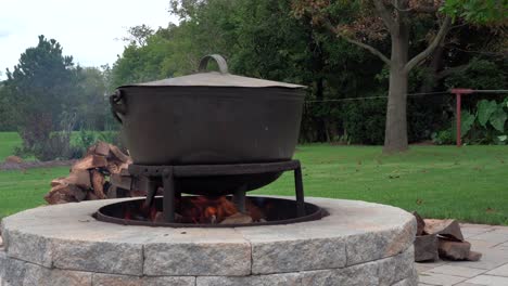 an old fashioned iron kettle over the fire of an outdoor campfire