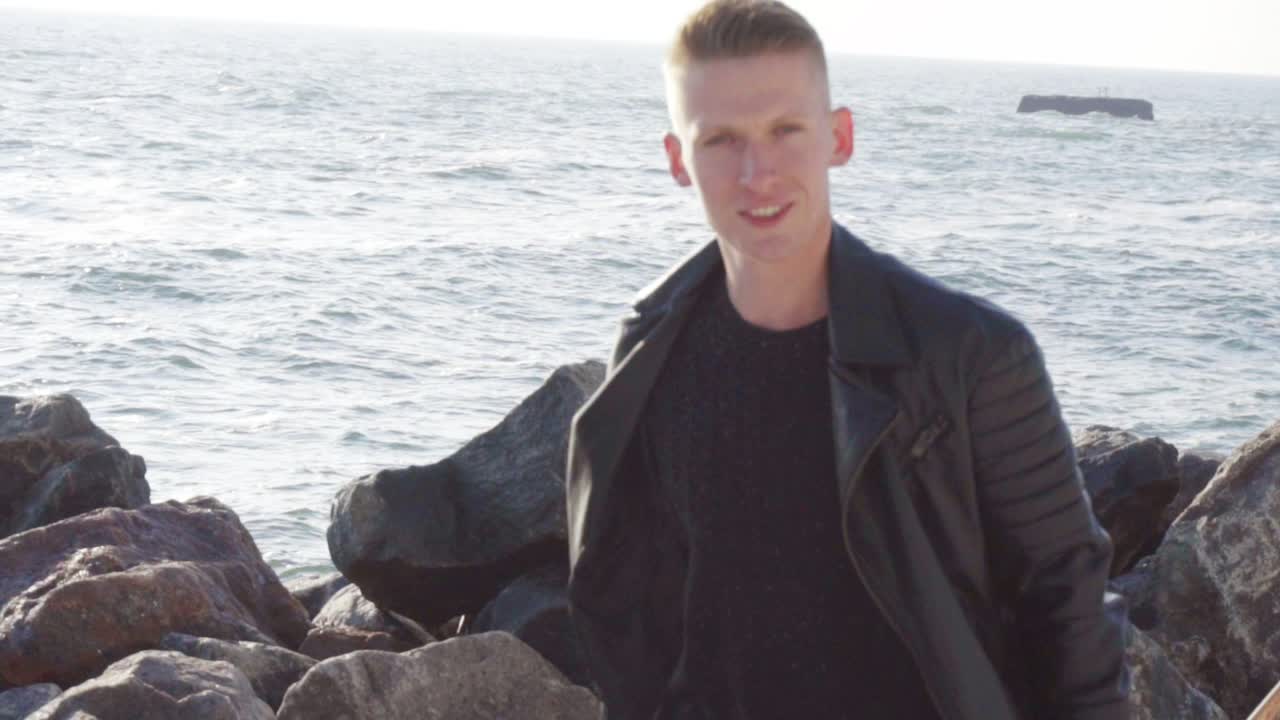 젊은 남자가 롱보드를 들고 미소 짓고 있습니다.