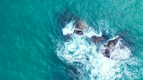 Schaumige-Wellen-Schlagen-Auf-Die-Felsbrocken-Im-Aquamarinfarbenen-Meer