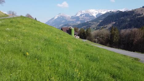 prado verde con granja y vista de las montañas en suiza en tiempo soleado
