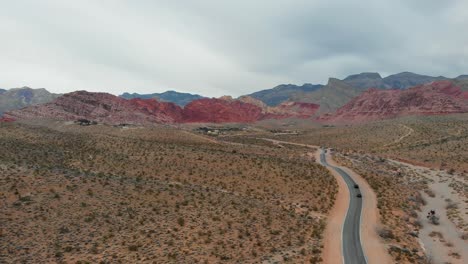 aerial drone shot of a desert highway with scenic mountains in the background