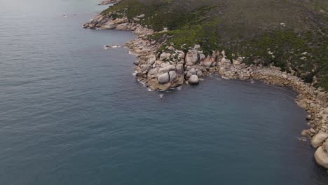 drone aerial slow fall and pan over beautiful blue water and white rocks on a sunny day in wilsons promontory