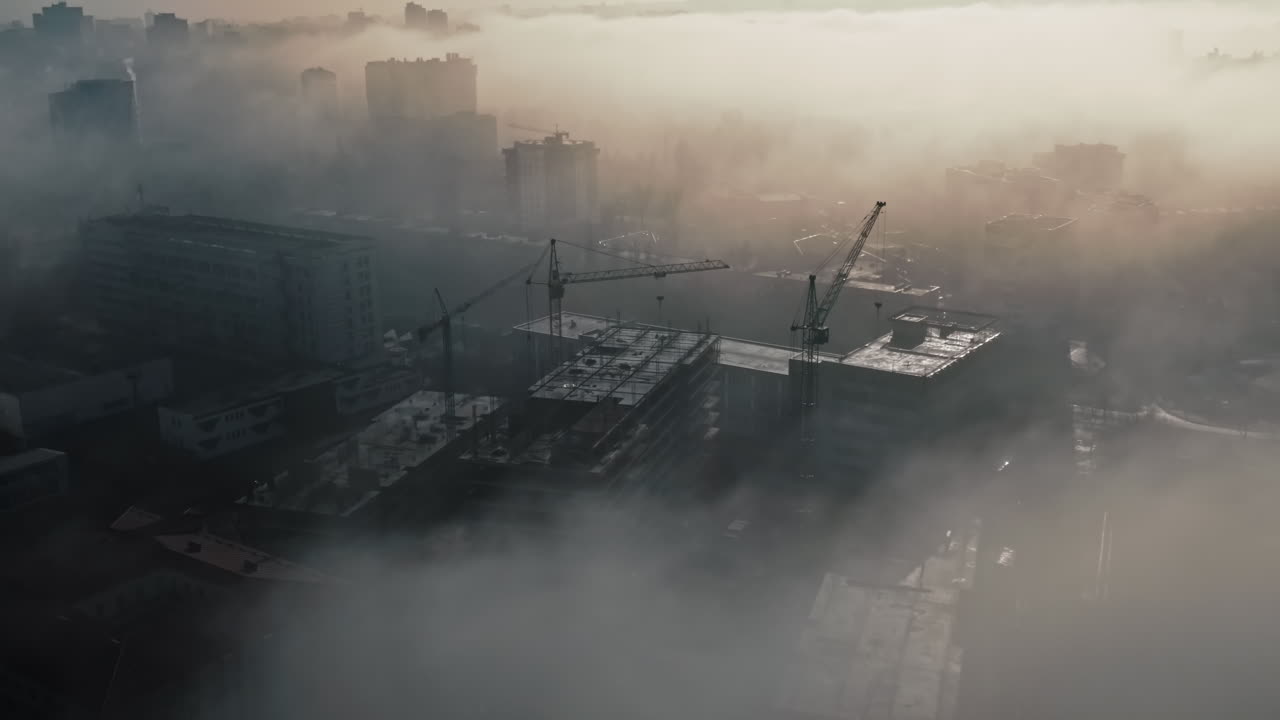 Aerial drone view above the clouds with buildings and construction works visible through, Chisinau, Moldova