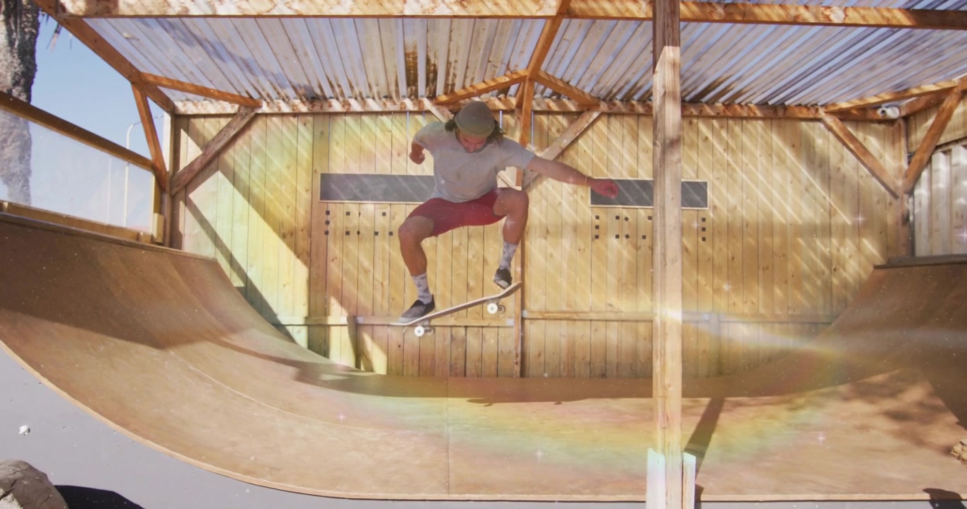 Male skateboarder pushing off wooden halfpipe and ollieing under sunlight while practicing trick