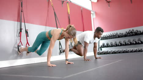 fit young caucasian woman and african american man exercising at the gym