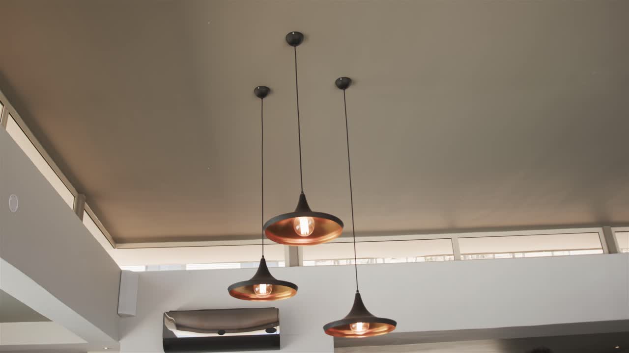 Pendant lamps swinging after minor disturbance in interior design, bulbs glowing, settling