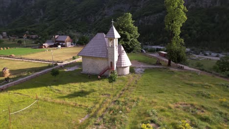 Alpine-village-church-on-green-meadow-surrounded-by-high-mountains-in-Theth,-Albania