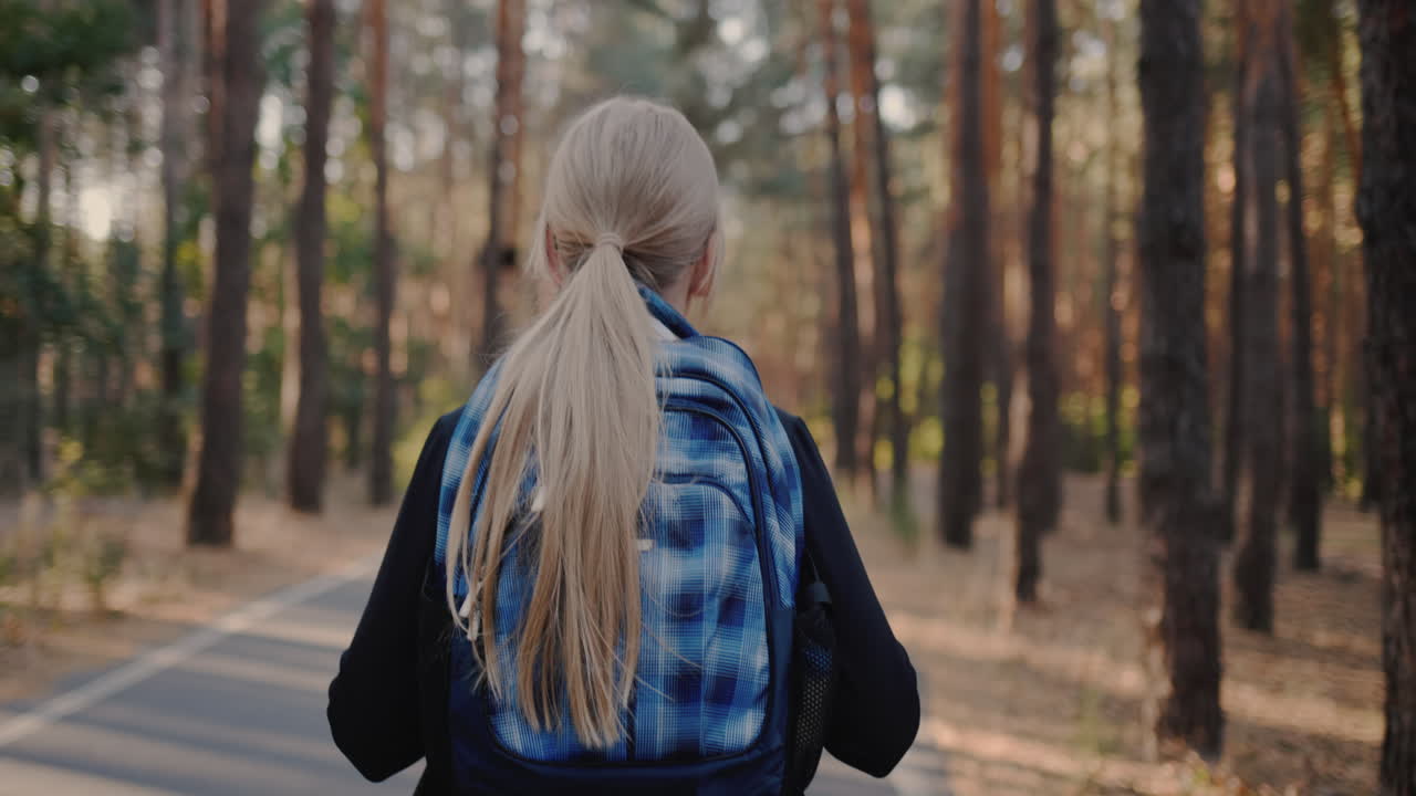 배낭을 메고 키 큰 나무가 있는 공원을 혼자 걷는 아이