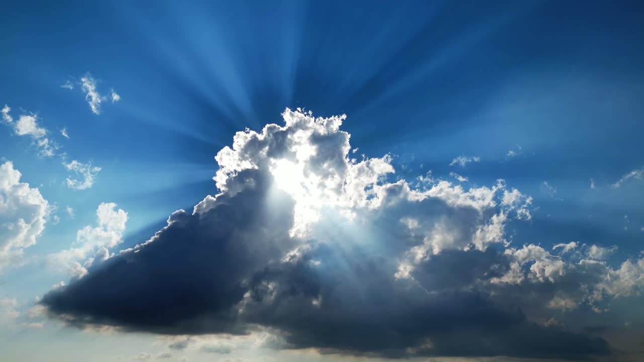 Paesaggio nuvoloso diurno con cumuli a lento movimento e potenti raggi solari che filtrano attraverso cieli dalla texture drammatica.